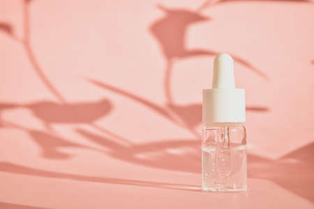Cosmetic aromatic oils in bottles with a pipette on a pink background with shadow. The concept of natural eco-cosmetics.の写真素材