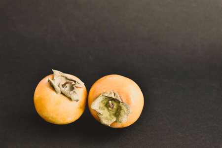 Ripe persimmon on a black table. Top view.