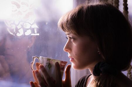 a young women is drinking tea near the windowの写真素材
