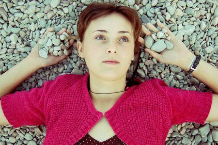 young woman lying on the sea pebbles on the beach view from the top