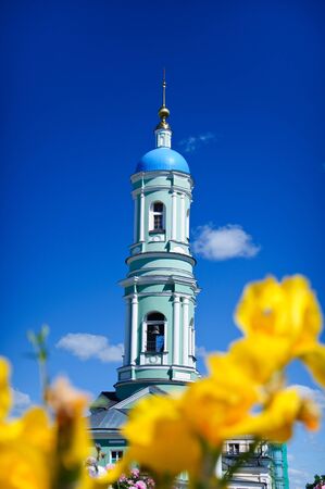monastery bell tower on the background of flowers and blue skyの写真素材