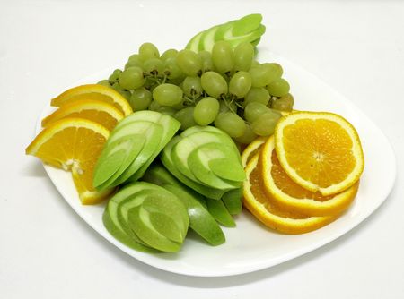 dish of cut fruits with apples, oranges and grapesの写真素材