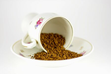porcelain cup with spill granulated coffeeの写真素材