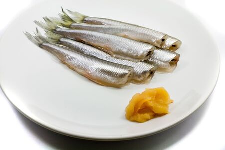 freh small scale fish with caviar on white plateの写真素材