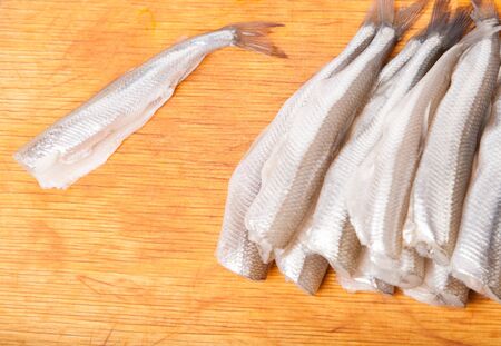 many uncooked trunk small fish on wood board