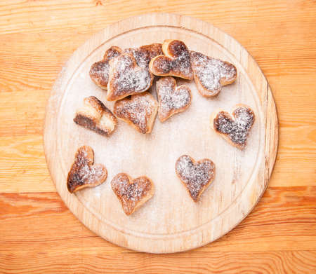 bakery hearts from split pastry with sugar powder on wooden boardの写真素材