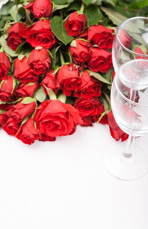 background with red roses and wine glass on whiteの写真素材
