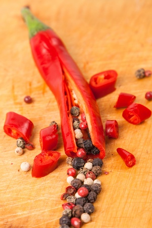 cut hot capsicum chili pepper and peppercorn on wooden boardの写真素材