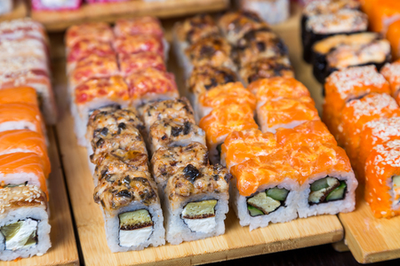 assortment sushi and rolls on wood board in dark lightの写真素材