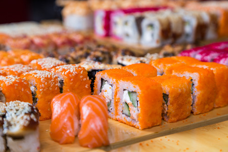 assortment sushi and rolls on wood board in dark lightの写真素材