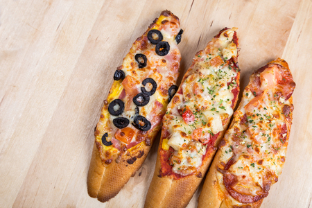 assorti bruscjetta with sausage, cheese, tomato fron big white baguette on wooden backgroundの写真素材