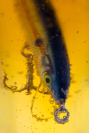 closeup fishing bait wobbler in glass with light beerの写真素材