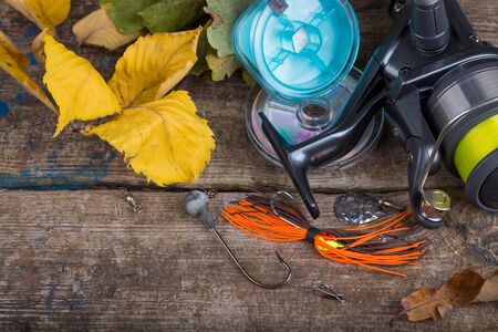 top fishing tackles reel, line and lure on wooden board with leafs of autumnの写真素材