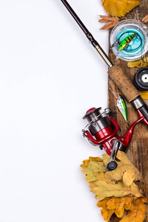 fishing tackles reel, line and lure on wooden board with leafs of autumnの写真素材