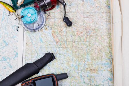 preparation in fishing journey with fishing tackles and gps navigator on map background