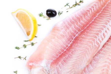 uncooked raw fillet of pangasius with lemon and olive on white backgroundの写真素材