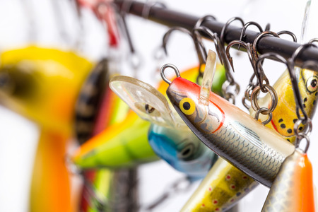 closeup different bright colored fishing bait wobblers be suspended on rod`s blank with white backgroundの写真素材