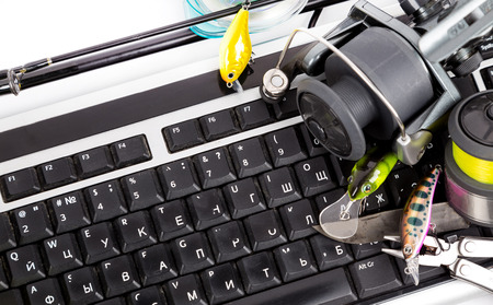 different fishing tackles on computer keyboard with white background. Concept design for freshwater...