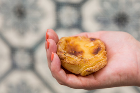 Traditional Portuguese egg tart pasty cake dessert Pasteis de nata in women hand. On background...