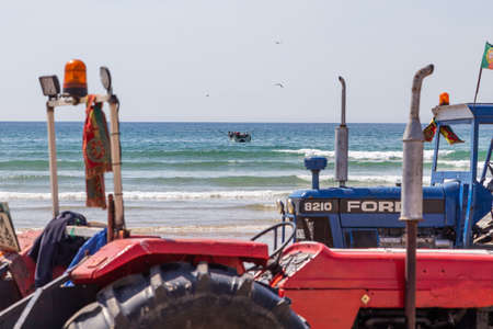 Costa da Caparica, Portugal - September 10, 2020: An artel of fishermen trawls fish from the tourist beach using a tractors. Vacationers watch and help.のeditorial素材
