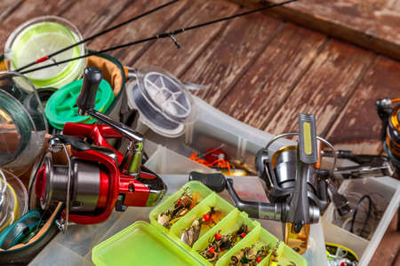 Different fishing tacles with rod and reels on wooden brown background. Mockap for advertisment and publishing.の写真素材
