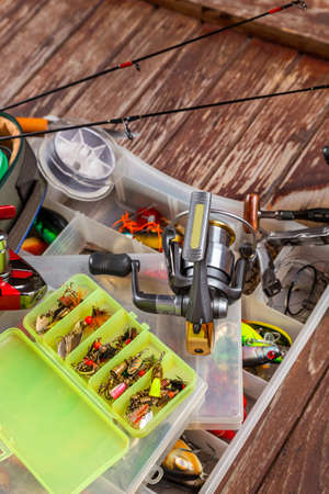Different fishing tacles with rod and reels on wooden brown background. Mockap for advertisment and publishing.の写真素材