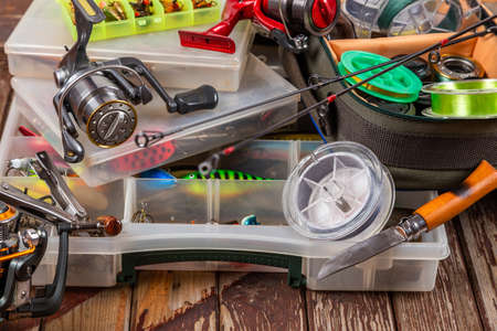 Different fishing tacles with rod and reels on wooden brown background. Mockap for advertisment and publishing.の写真素材