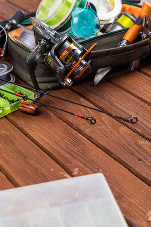 Different fishing tacles with lures and reels on wooden brown background with place for text. Design...