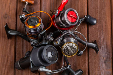 Different fishing tacles with lures and reels on wooden brown background with place for text. Design for advertisment and publishing.の写真素材