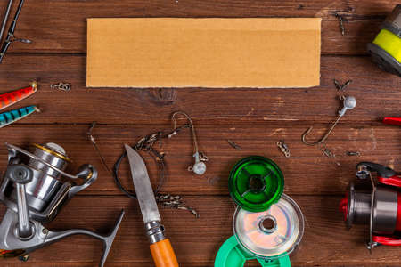 Different fishing tacles with lures and reels on wooden brown background with place for text. Design for advertisment and publishing.の写真素材