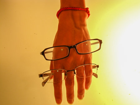 Glasses on the hand of a girl on a yellow background.の写真素材