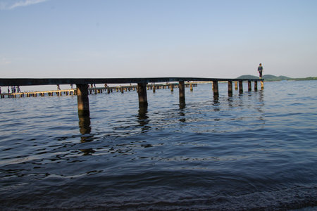 wooden pier in the sea with a person standing on the pierの写真素材