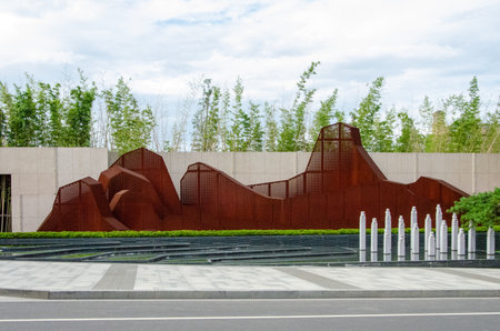 HANGZHOU, CHINA - JULY 03, 2017: A wide view of a modern landscape feature in a residential community. It displays an abstract mountain range made of rusty Corten steel sheets, set against a bamboo forest background with small fountains in the foreground.のeditorial素材