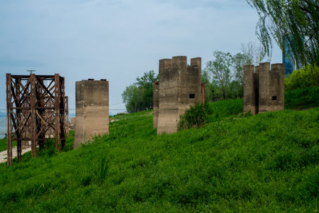 A wide perspective of abandoned concrete structures and metal frames remaining on a green grassy...