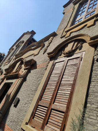 A detailed architectural perspective showing the masonry and arched window frames of a classical gray brick building in an urban setting.の写真素材