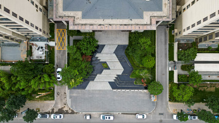 A top-down aerial shot of a residential building entrance plaza with structured stone patterns and...