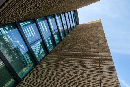 Description: An upward perspective of a modern building facade featuring alternating stone sections...
