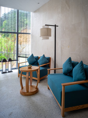A cozy seating area in a modern building, featuring blue sofa sets, a wooden coffee table, and large...