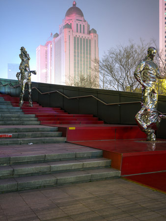 Wuhan, China - March 8, 2025: Vertical view of silver artistic sculptures situated on a red outdoor staircase. The image shows a modern building with a dome and bare trees in an urban setting.のeditorial素材