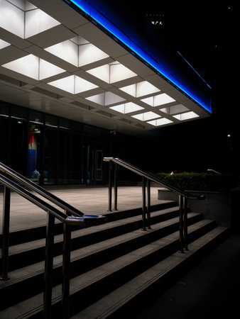 Wuhan, China - March 21, 2025: A modern building entrance featuring stairs and a canopy with an illuminated square grid ceiling. The image shows architectural geometry and lighting design at night.のeditorial素材