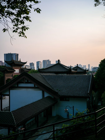 Wuhan, China - May 19, 2025: Traditional Chinese buildings with white exterior walls, dark tiled roofs and covered walkways seen from an elevated angle. The image contrasts historic cultural architecture with modern city high-rises under a clear sky.のeditorial素材
