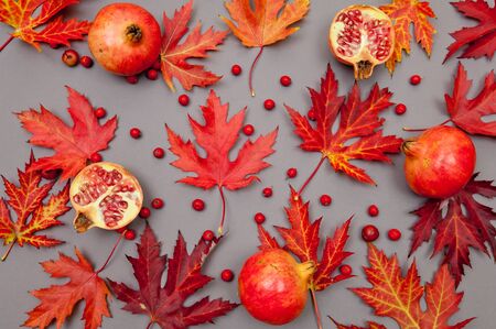 Pomegranates and autumn red fallen leaves pattern on grey backgroundの写真素材
