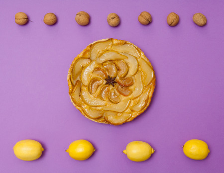 Whole tarte Tatin apple and pear tart pie with fruits on purple background with copy spaceの写真素材
