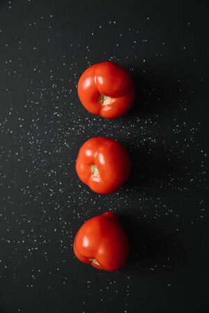 Fresh raw tomatoes on dark black background. top viewの写真素材