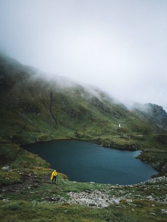 Hiker in a yellow jacket walking in a foggy mountains near the glacier Capra lake , Fagaras,Romaniaの写真素材