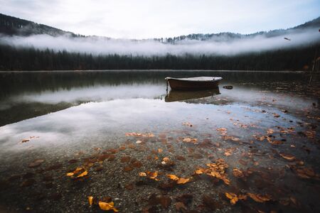 Autumn landscape wallpaper with a rowboat on lakeの写真素材