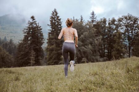Young fitness woman running at forest trailの写真素材