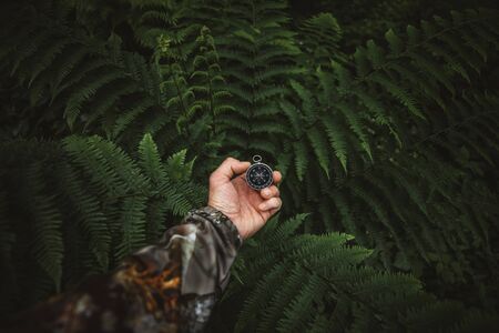 Survivor man searching the directions with compass in the wilderness green forestの写真素材