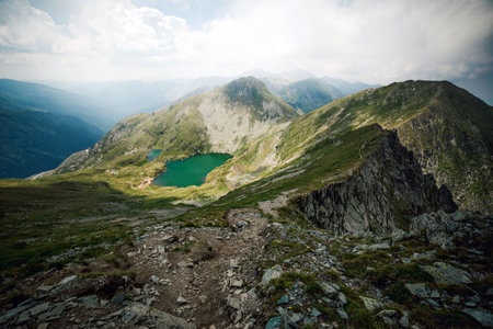 summer landscape with lake on high altitude. beautiful scenery of fagaras mountain ridge in summer. open view in to the distant peak beneath a fluffy clouds. Capra lacul, Romaniaの写真素材
