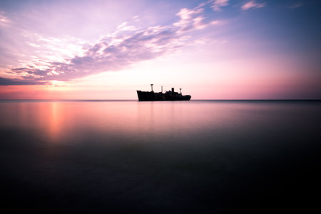 Sunset over the sea with ship silhouette and reflection in water.の写真素材